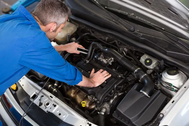 A mechanic inspecting the engine under the hood of a car